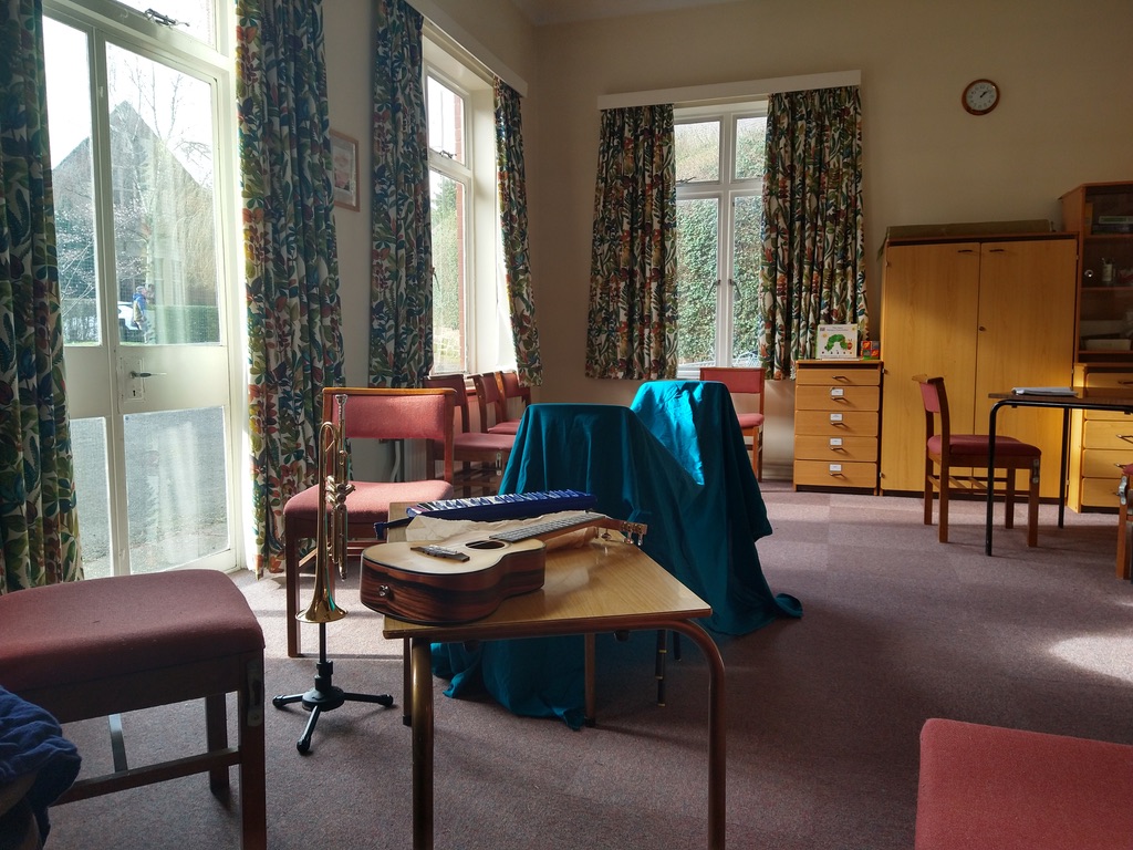Photo of messy room, with ukulele splayed across a table.