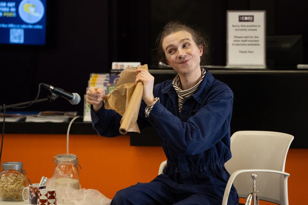 Photo of Isaac pulling a face and holding paper to a microphone