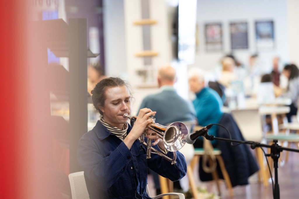 Photo of Isaac playing Flugelhorn in a cafe and in costume